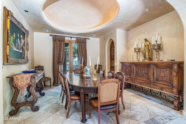 dining room featuring a raised ceiling and french doors