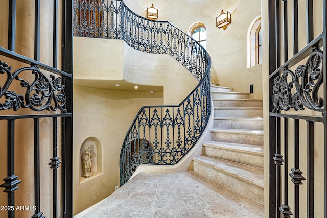 stairway featuring a towering ceiling