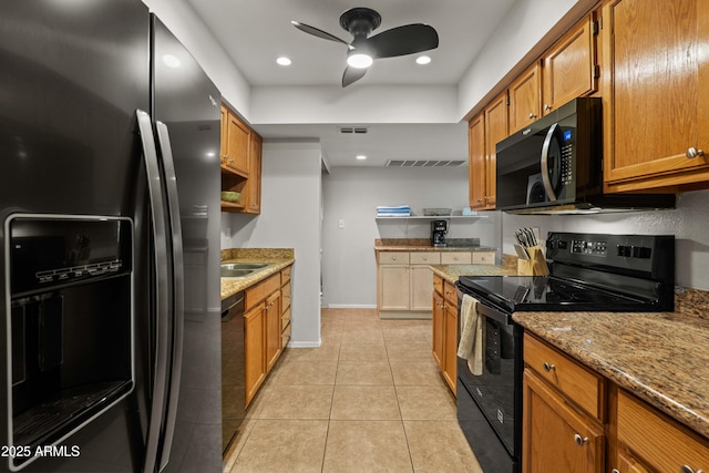 kitchen with black appliances, brown cabinets, ceiling fan, light tile patterned flooring, and light stone counters
