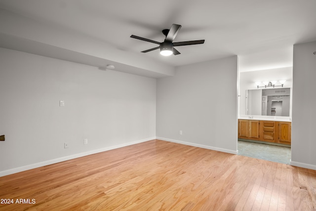 empty room with ceiling fan and light hardwood / wood-style floors