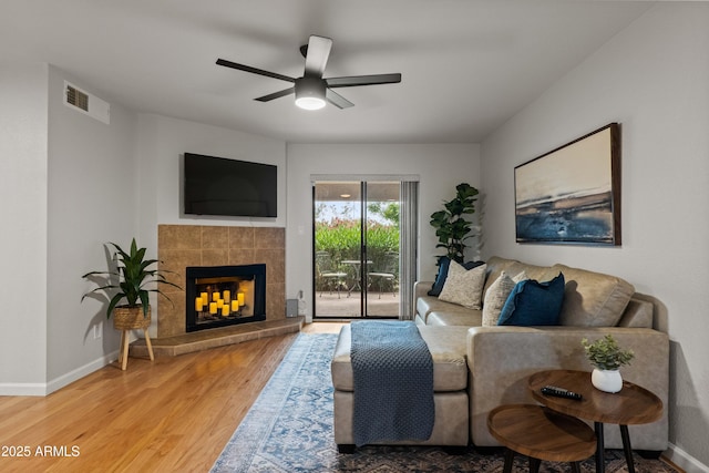 living area with wood finished floors, a fireplace, baseboards, and ceiling fan