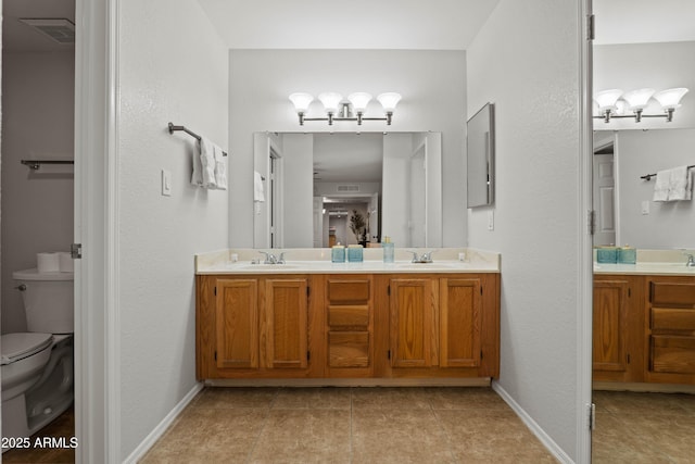 bathroom with toilet, a chandelier, double vanity, tile patterned flooring, and baseboards