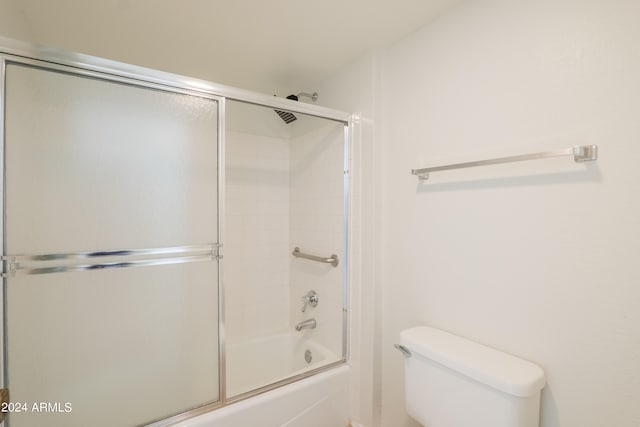 bathroom with toilet and shower / bath combination with glass door