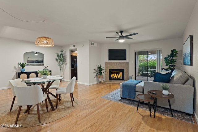 living area featuring ceiling fan, light wood finished floors, and baseboards