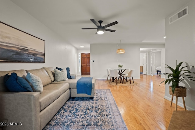 living room with wood finished floors, a ceiling fan, and baseboards
