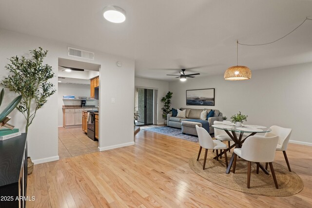 dining area with light wood-type flooring, a ceiling fan, and baseboards