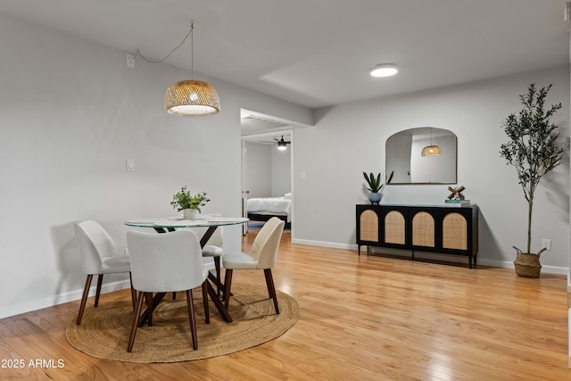 dining area featuring light wood-type flooring, baseboards, and arched walkways