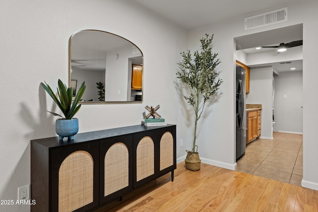 hallway with arched walkways, light wood-style flooring, and baseboards