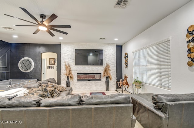 living room with a stone fireplace and ceiling fan