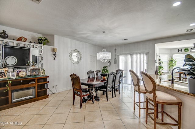 tiled dining space with a textured ceiling and a chandelier