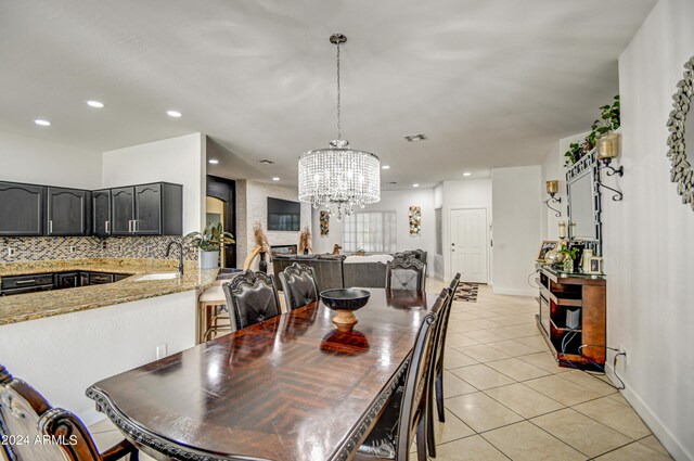 dining area featuring light tile patterned flooring, sink, and a notable chandelier