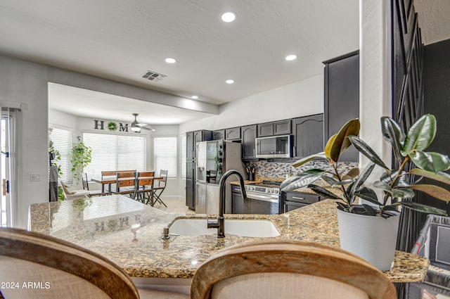 kitchen featuring sink, ceiling fan, stainless steel appliances, and stone countertops