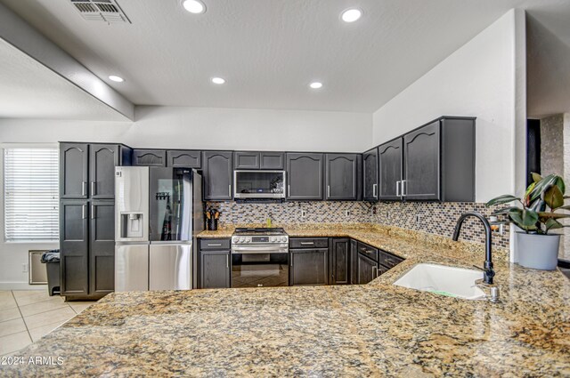 kitchen with stainless steel appliances, sink, light stone counters, light tile patterned floors, and backsplash