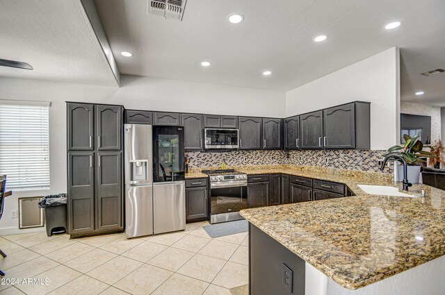 kitchen featuring stainless steel appliances, light stone counters, tasteful backsplash, and sink