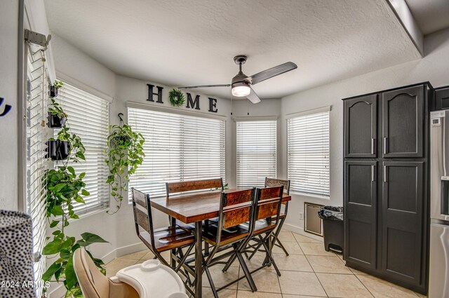 tiled dining space with a textured ceiling and ceiling fan