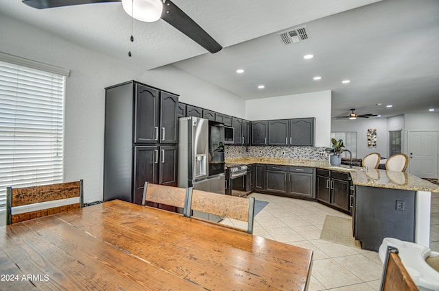 kitchen featuring tasteful backsplash, stainless steel appliances, light stone counters, kitchen peninsula, and ceiling fan