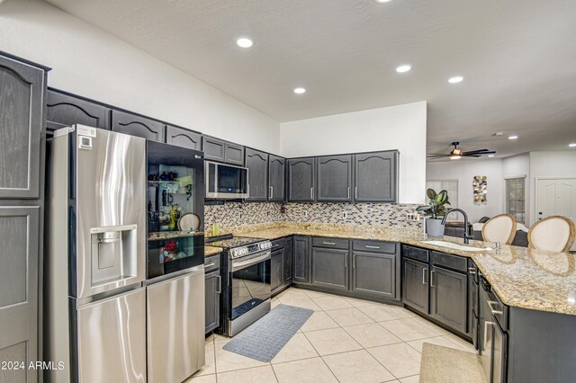 kitchen with backsplash, kitchen peninsula, appliances with stainless steel finishes, and ceiling fan