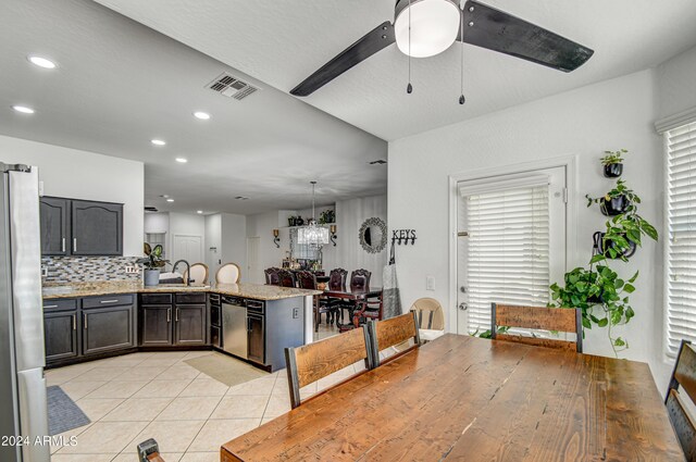 kitchen featuring light tile patterned flooring, ceiling fan with notable chandelier, sink, kitchen peninsula, and backsplash