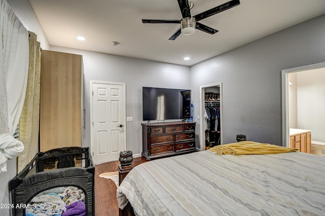 bedroom with a spacious closet, connected bathroom, hardwood / wood-style flooring, ceiling fan, and a closet