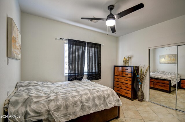 tiled bedroom with ceiling fan and a closet