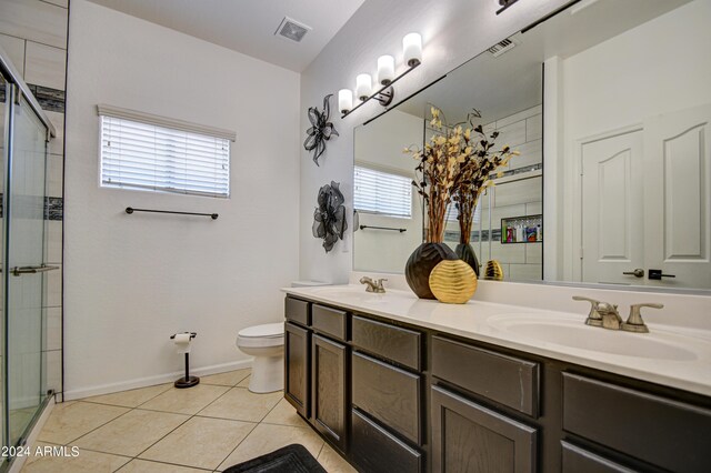 bathroom with a shower with door, tile patterned flooring, toilet, and double sink vanity