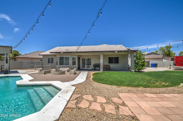 rear view of property featuring an outdoor fire pit, a patio area, a fenced in pool, and a yard