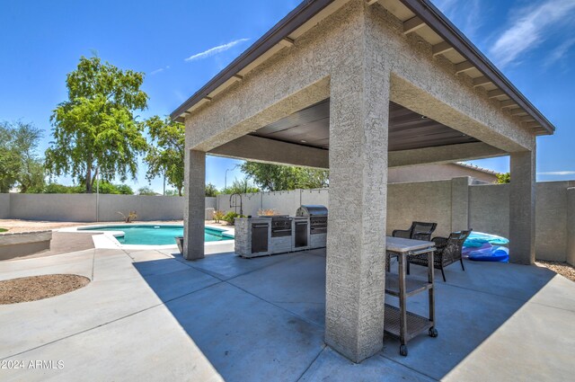 view of patio with area for grilling, a fenced in pool, and exterior kitchen