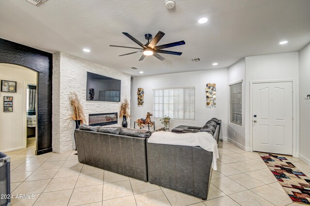 tiled living room with a fireplace and ceiling fan