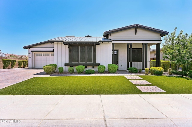 view of front of property with a porch, a garage, and a front lawn