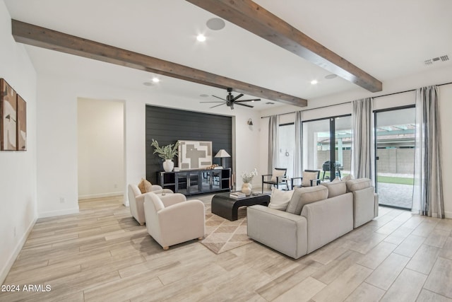 living area featuring light wood finished floors, baseboards, visible vents, and beam ceiling