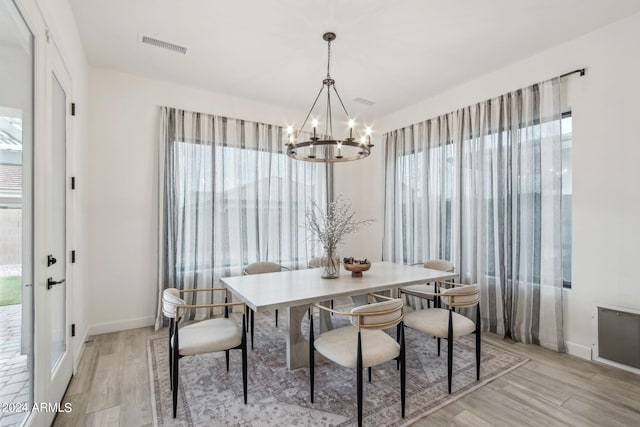 dining area featuring a chandelier, light wood-type flooring, visible vents, and a healthy amount of sunlight