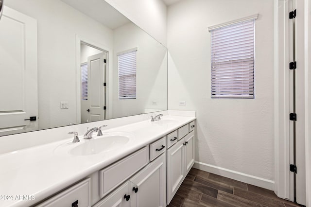 bathroom featuring double vanity, wood tiled floor, baseboards, and a sink