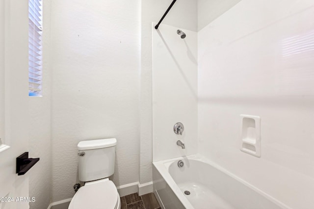 bathroom featuring toilet, washtub / shower combination, baseboards, and wood finished floors