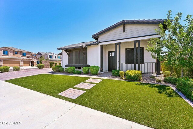 view of front of house featuring a garage, covered porch, and a front lawn