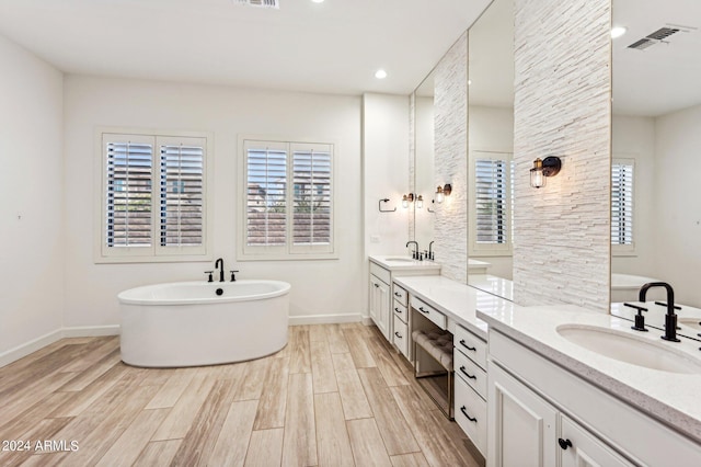 full bath featuring a freestanding tub, visible vents, vanity, and wood finished floors