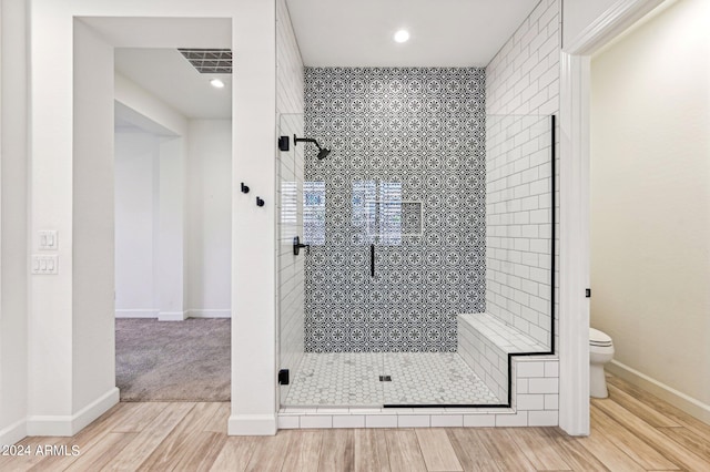 full bathroom featuring visible vents, baseboards, toilet, wood finished floors, and a shower stall