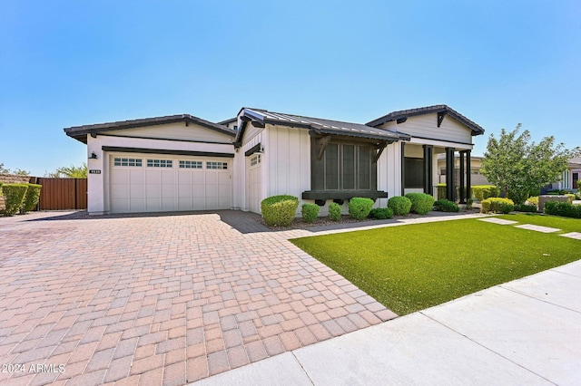 view of front of home featuring an attached garage, a standing seam roof, decorative driveway, a front lawn, and board and batten siding