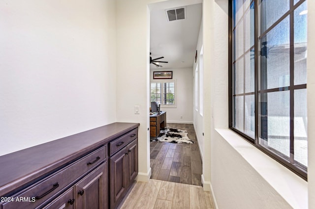 hall featuring visible vents, baseboards, and wood finished floors