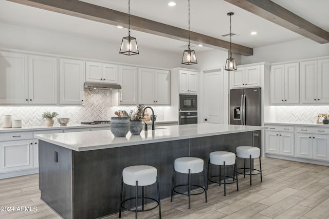 kitchen featuring stainless steel appliances, wood finish floors, a sink, white cabinets, and a center island with sink