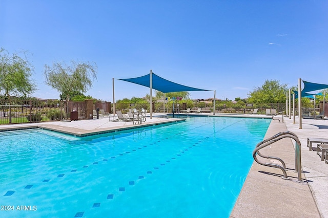 community pool with a patio area and fence