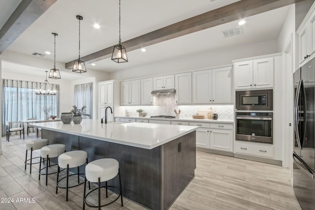 kitchen featuring tasteful backsplash, visible vents, stainless steel appliances, under cabinet range hood, and beam ceiling