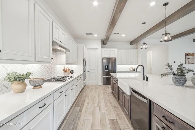 kitchen with appliances with stainless steel finishes, a sink, white cabinets, and under cabinet range hood