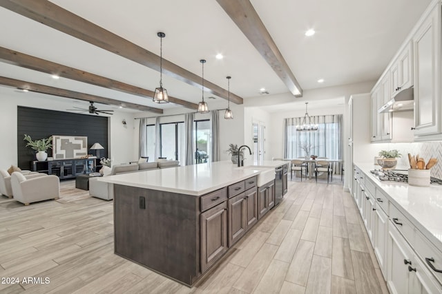 kitchen featuring a sink, white cabinets, dark brown cabinets, light countertops, and wood tiled floor