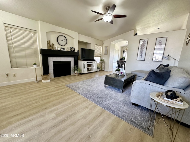 8673 W Palm Ln, Phoenix, AZ 85037 - living area featuring arched walkways, a ceiling fan, wood finished floors, a fireplace, and lofted ceiling