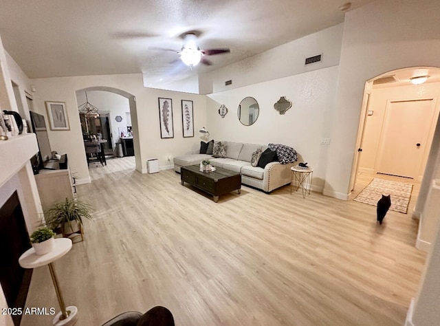 8673 W Palm Ln, Phoenix, AZ 85037 - living area with arched walkways, ceiling fan, light wood-style floors, and a fireplace