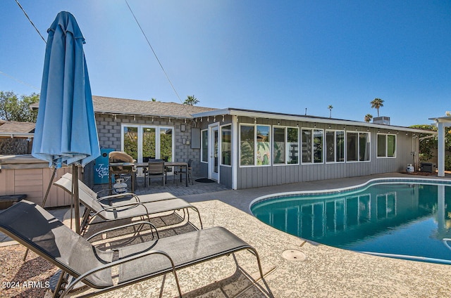 view of swimming pool with a patio and a sunroom