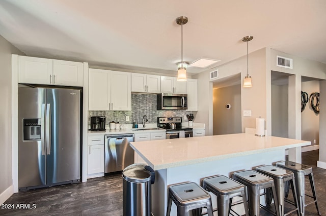 kitchen featuring dark hardwood / wood-style floors, appliances with stainless steel finishes, tasteful backsplash, decorative light fixtures, and white cabinetry