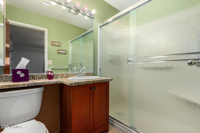 bathroom featuring an enclosed shower, vanity, and toilet