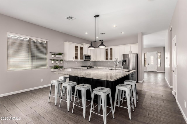 2409 W Red Range Way, Phoenix, AZ 85085 - kitchen with stainless steel appliances, a large island with sink, baseboards, white cabinetry, and tasteful backsplash