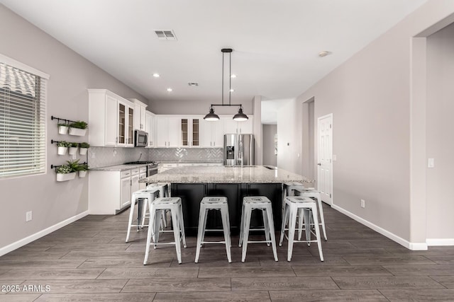 2409 W Red Range Way, Phoenix, AZ 85085 - kitchen with stainless steel appliances, dark wood finished floors, a kitchen island, decorative backsplash, and white cabinets